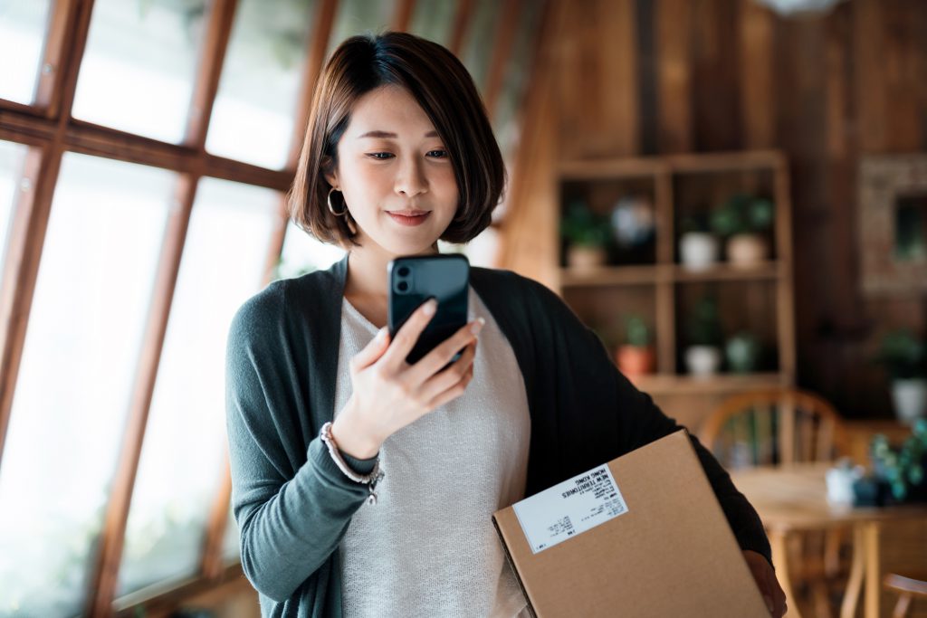 Smiling young Asian woman shopping online with smartphone on hand, Engineer open ERP(Enterprise Resource Planning) System in Singapore